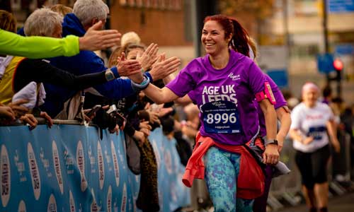 Woman giving high fives to the crowd whilst running in the ϲʿֱLeeds Abbey Dash